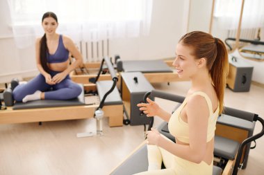 Katılımcılar bir stüdyoda enerji ve arkadaşlıkla dolu canlı bir pilates seansına katılıyorlar..