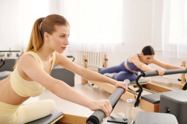 Odaklanmış bireyler modern bir stüdyoda yenilikçi makineler kullanarak pilates çalışmalarına girişirler..