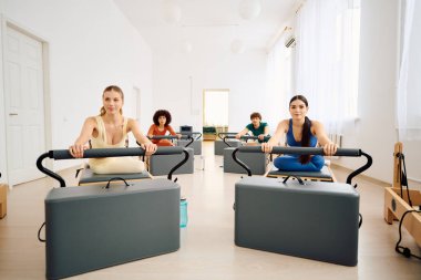 Sakin bir stüdyoda dört kişi pilates dersinde güç ve odaklanma gösteriyor..