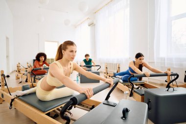 Katılımcılar yoğun bir şekilde modern, havadar bir stüdyo ortamında pilates çalışmalarına odaklanıyorlar..