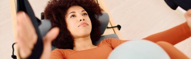 Bir insan iyi donanımlı bir stüdyo ortamında pilates yaparken dikkatle odaklanır..
