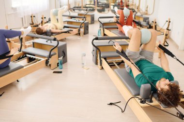 Katılımcılar, gücünü artırmak için yenilikçi teçhizat kullanan odaklanmış bir pilates sınıfına katılıyorlar.