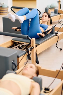 İki kişi pilates yapıyor, dingin bir stüdyo ortamında güç ve konsantrasyon sergiliyor..