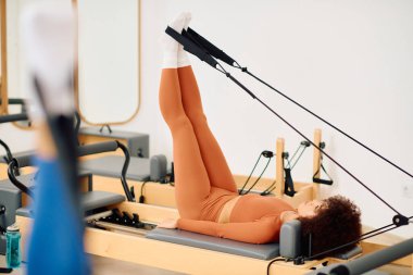Bireyler çekirdek istikrar ve dayanıklılığını artırmak için bir reformcu üzerinde hedefli bir pilates çalışması gerçekleştirirler..