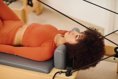 Kendini bir reformcu üzerinde pilates yapmaya adamış bir bireye odaklanın. Sağlığı ve dengeyi teşvik edin..