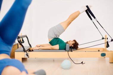 Katılımcılar özlerini özel ekipmanlarla parlak bir stüdyoda pilates yaparak güçlendiriyorlar..