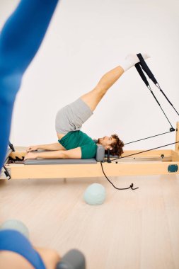 Katılımcılar güç ve esneklik egzersizleriyle dinamik bir pilates oturumuna katılıyorlar.