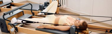 Kendini adamış bir atlet dinamik pilates yapar, sakin bir stüdyoda güç ve esneklik gösterir..