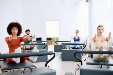 Katılımcılar stüdyodaki pilates ekipmanlarını kullanarak çekirdek gücünü ve esnekliğini artırıyorlar..