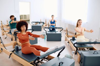 Katılımcılar reformcular üzerinde yapılan pilates egzersizlerine katılarak güç ve esnekliği artırıyorlar.
