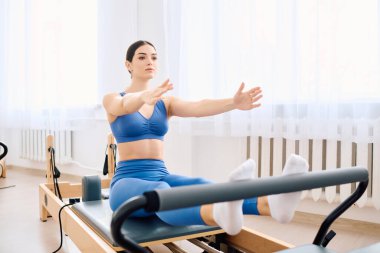 Reformcu üzerinde pilates yapan biri, gücünü göstererek sakin bir stüdyoya odaklanır..