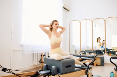 Pratisyen, çekirdek gücünü ve esnekliğini parlak ve hoş bir pilates stüdyosunda gösteriyor.