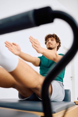Erkek bir atlet pilates antrenmanına katılır. Parlak stüdyo ortamında vücut kaslarını güçlendirir..