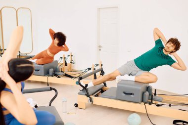 Parlak bir pilates stüdyosunda, bireyler güç ve esnekliği artırmak için reformcular üzerinde çalışırlar..