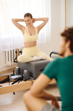 Bir kadın, ışıkla çevrili bir pilates stüdyosunda gerinirken bir anlık rahatlamanın tadını çıkarır..