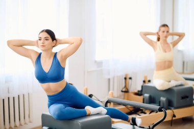 Kendini işine adamış iki kişi parlak ve ferah bir stüdyoda pilates çalışmasına girişiyor..