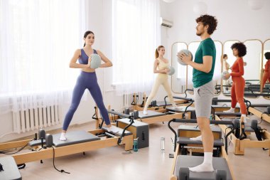 Katılımcılar reformcular üzerinde çeşitli pilates egzersizleri yaparak güç ve esnekliği vurguluyorlar.