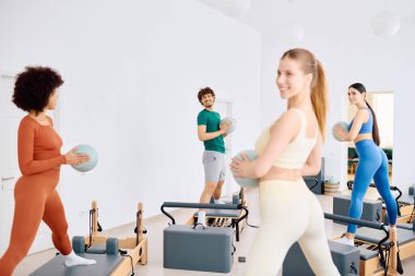 Dört kişi, parlak bir stüdyoda atletizm ve arkadaşlığı gösteren canlı bir pilates dersinden zevk alıyor..