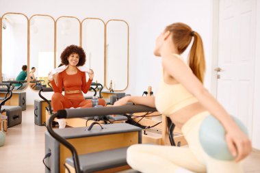 İki kadın pilates seanslarının keyfini çıkarıyorlar. Parlak bir stüdyoda arkadaşlığı ve motivasyonu teşvik ediyorlar..