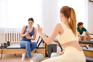 İki kişi spor yaparken aktif olarak dinamik pilates dersine katılıyor.