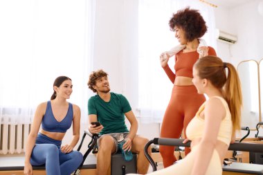 Güneşli bir pilates stüdyosunda arkadaşlar, enerjik bir dersten sonra gülümsemeyi ve cesaretlendirmeyi paylaşırlar..