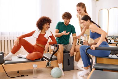 Dört arkadaş, iyi aydınlatılmış bir pilates stüdyosunda toplanıp antrenmanlarından sonra bahşiş ve kahkaha paylaşıyorlar..