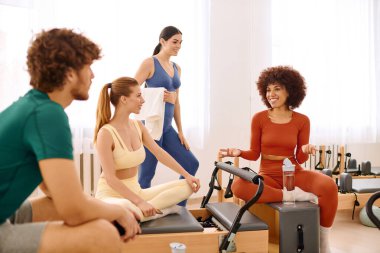 Arkadaşlar pilates yapıyor, tüyoları paylaşıyor ve güneşli bir stüdyoda gülüyorlar..