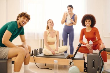 Güneşli bir stüdyoda dört arkadaş pilates dersinde kahkaha ve enerjiyi paylaşıyor..