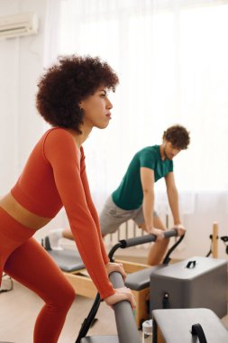 İki birey dikkatle pilates egzersizlerine odaklanırken yenilikçi makineler kullanıyor..