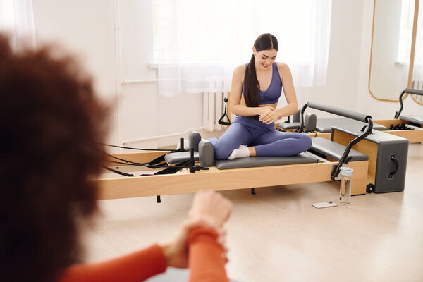 Участники концентрируются на пилатесе в яркой студии, повышая гибкость и силу.