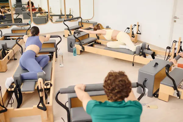 Katılımcılar, modern bir stüdyoda pilates yaparken esneklik ve gücü artırıyorlar..