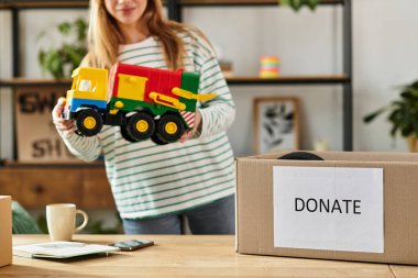 A young woman sorts through toys, preparing to donate them for a sustainable lifestyle. clipart