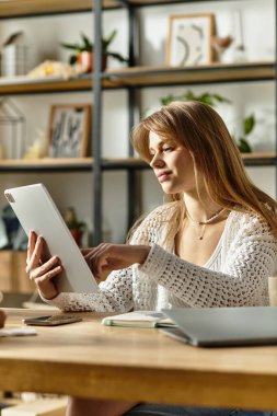 Genç bir kadın aktif olarak kıyafet bağışlıyor, tablet kullanıyor ve evde sürdürülebilir bir yaşam tarzını benimsiyor..