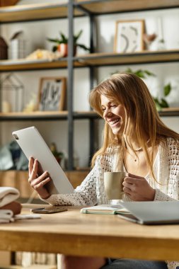Genç bir kadın sıcak içkisinin tadını çıkarırken online bağışta bulunuyor..