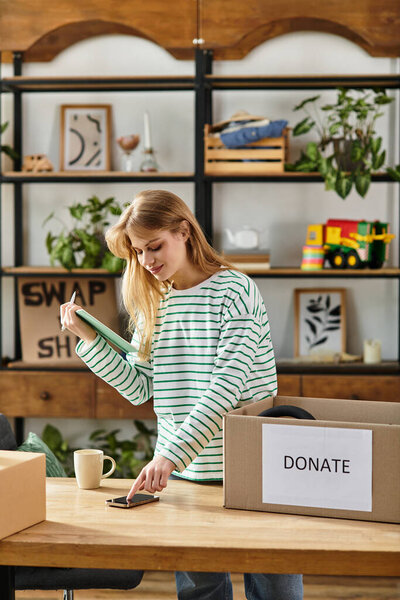 A young woman sorts clothes for donation, using smartphone, sustainable living.