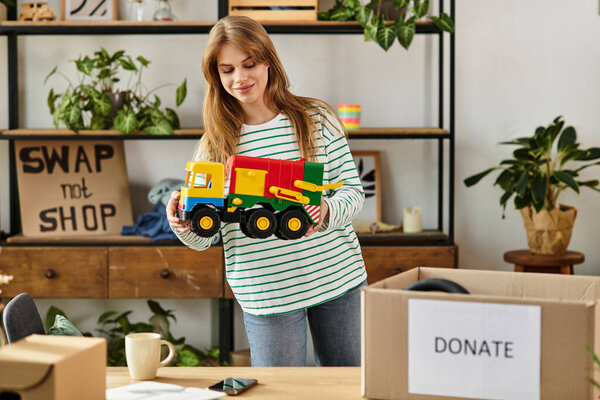 Красивая молодая женщина организует игрушки для пожертвований, чтобы способствовать устойчивой жизни в доме.