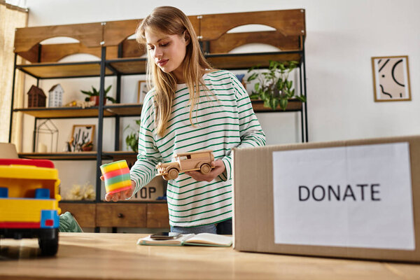 Pretty young woman carefully sorts out toys and clothes for donation while promoting sustainability.
