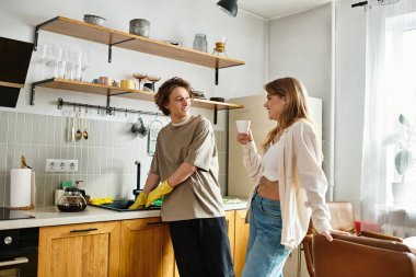 Bir çift, şık mutfaklarında ev işleri yaparken eğlenceli bir anın tadını çıkarıyor..