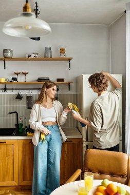 Şık bir mutfakta, sevgi dolu bir çift yemek hazırlarken ve gülümserken keyifli anları paylaşır..