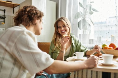 Genç bir çift evde taze meyvelerle çevrili güzel bir kahvaltı yapıyor..
