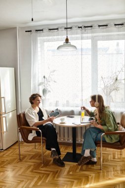 Genç bir çift sıcak masalarında keyifli bir anı paylaşıyor, sıcak içkilerin ve kahkahaların tadını çıkarıyorlar..
