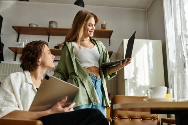 Sevecen eşler, rahat bir yaşam alanında dizüstü bilgisayarlarıyla uğraşırken şefkatli bakışlar atarlar..