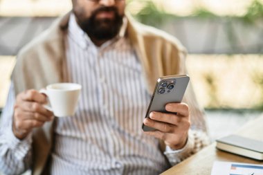 Çekici bir son sınıf öğrencisi bir fincan kahveyle rahat bir kafede akıllı telefonuyla takılıyor..