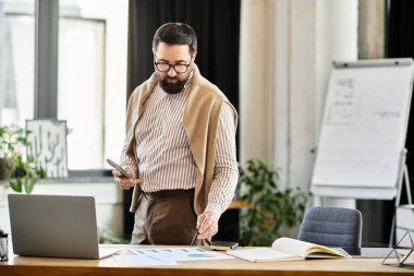 Çekici bir kıdemli adam bitkilerle dolu modern bir ofis ortamında çizelgeleri ve verileri inceliyor..