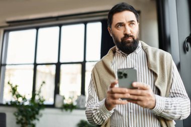 Yakışıklı yaşlı, doğal ışıkla dolu sıcak bir odada akıllı telefonuyla meşgul oluyor..