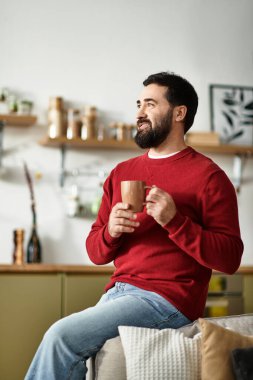 Yakışıklı, yaşlı bir adam sıcak bir içecekle rahatça oturur, rahat bir ortamda mutlu mesut gülümser..