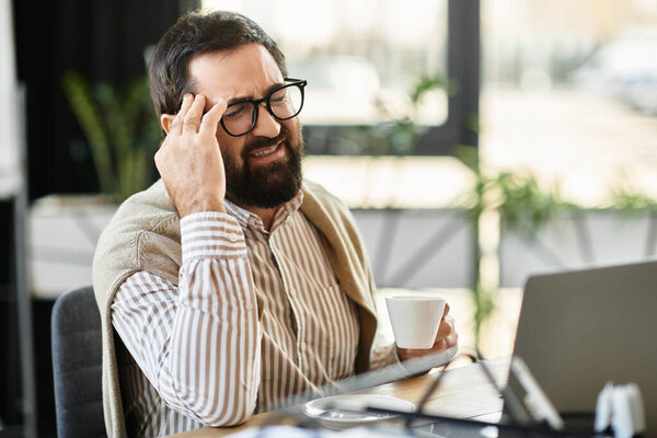 Handsome elderly man sips coffee thoughtfully in a bright, modern workspace.