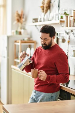 Yakışıklı, yaşlı bir adam şık bir mutfakta, aydınlık bir sabahta kahve yapar..