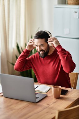 Gündelik kırmızı kazaklı yaşlı bir adam masasında internete bağlanırken mutlu bir anı paylaşıyor..