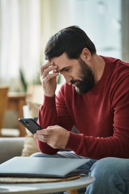 Yakışıklı son sınıf öğrencisi akıllı telefonuna bakarken düşüncelere dalmış görünüyor..